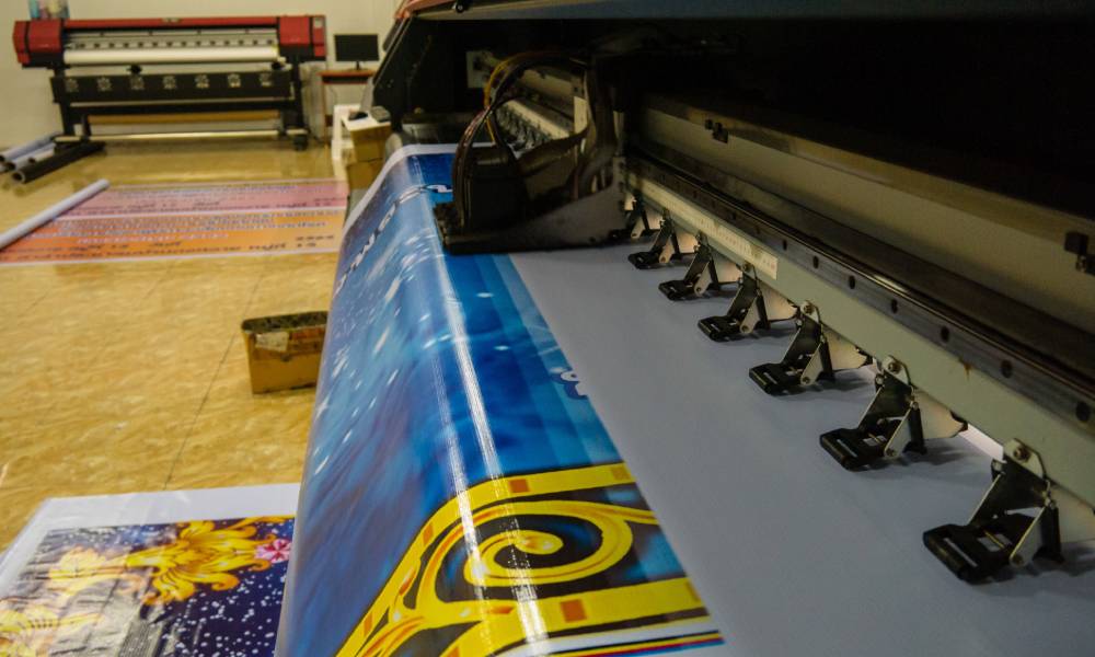 A wide format printer prints out a large, bright, and colorful print of a very fancy design in a clean room.