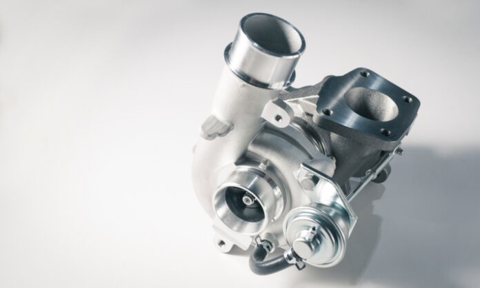 A new, unused turbocharger with detailed components and a sleek, modern design sits against a light background.