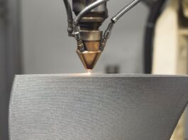 An up-close view of a 3D printer’s nozzle creating a steel object while utilizing high-temperature printing processes.