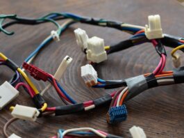 A close-up of multicolored wire bundles with connectors secured by black tape laid out on a wooden table.