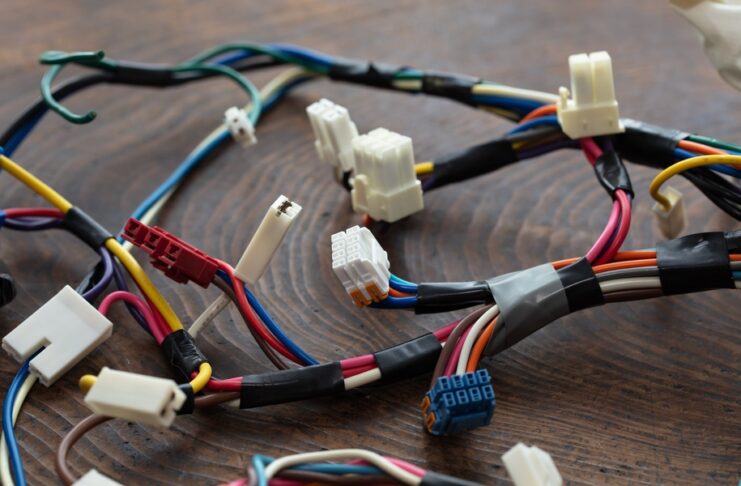 A close-up of multicolored wire bundles with connectors secured by black tape laid out on a wooden table.