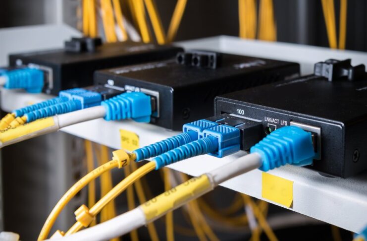 A black box has yellow and white wires with blue plugs, plugged into it. Yellow wires are blurry in the background.