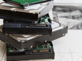 Eliminating Data: 5 Steps for Destroying Hard Drives Five stacked hard drives are lying on a white surface. Some of the hard drives have green, exposed internal components.