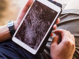 What Makes a Gadget Truly Durable: A Buyer’s Guide A man holds a tablet with a shattered touchscreen in one hand. He wears a blue shirt and tan shorts.