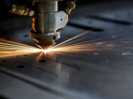 Precision Cutting’s Role in Tech Manufacturing A laser precision cutting machine slices through metal, producing sparks as it forms parts for electronic components.