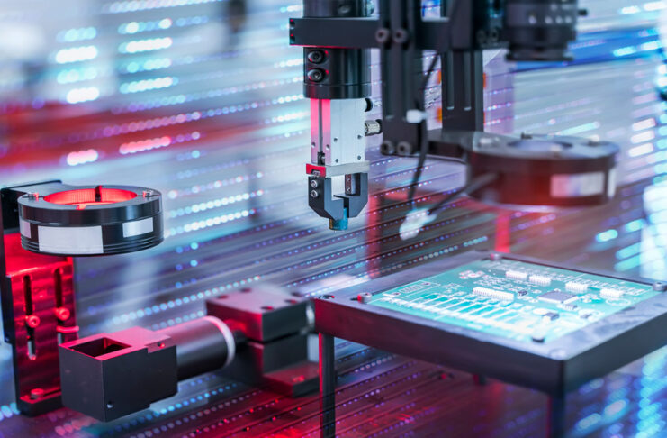 Automated manufacturing equipment with sensors performs precision work on a circuit board in a high-tech production facility.