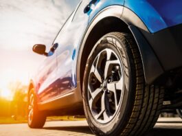 How IoT Tire Technology Will Shape the Future of Driving A blue car's front wheel with an alloy rim on a sunny pavement, showing modern tire and vehicle design.