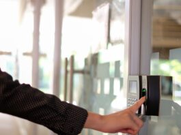 A professional reaching toward a biometric access control unit and placing their finger onto the fingerprint scanner.