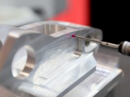 A close-up view shows a stylus probe with a clear, pink ball on the end working on a metal part.