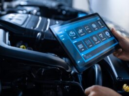 A mechanic using a tablet to conduct a diagnostic software review for different parts of the vehicle.