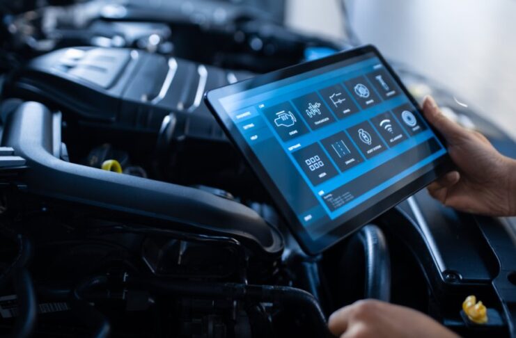 A mechanic using a tablet to conduct a diagnostic software review for different parts of the vehicle.