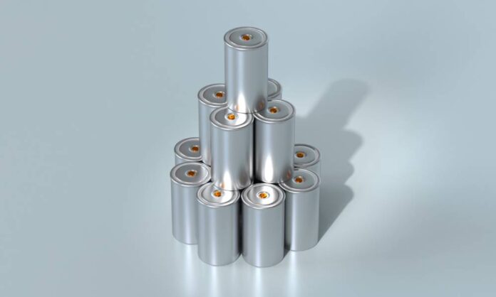 A stack of small silver lithium-ion batteries with small orange ends. The battery stack sits against a silver background.