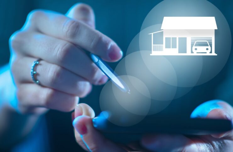 A person uses a smartphone as a glowing home and garage hologram appears above the screen in white light.