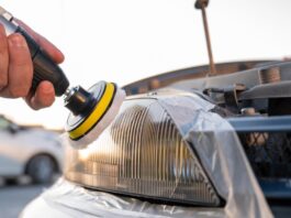 How New Technology Is Changing Auto Restoration A person using a polishing tool on a car headlight outdoors, with the vehicle's front and pavement nearby.